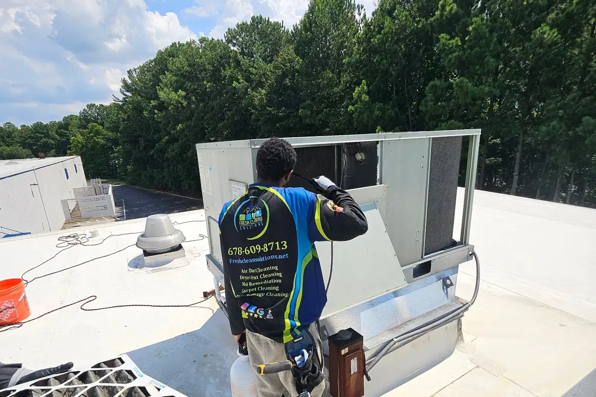 Fresh Cleaning Solutions technician working on an opened commercial rooftop HVAC unit