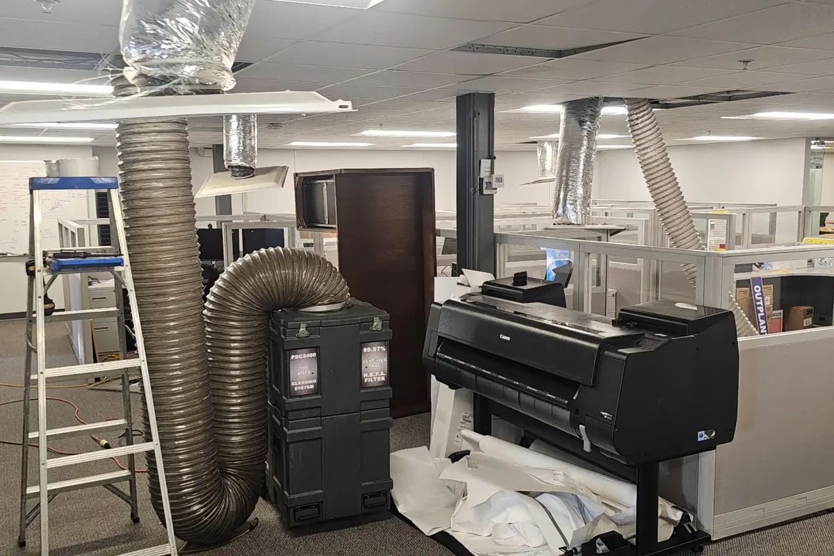 Negative-air duct cleaning machine and hoses set up in an office building