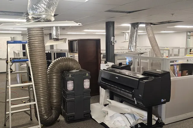 Negative-air duct cleaning machine and hoses set up in an office building