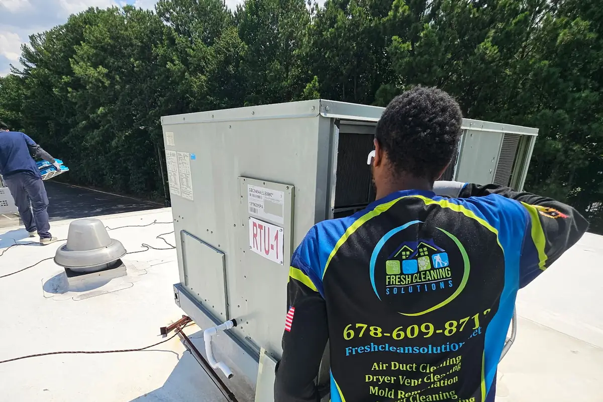 Fresh Cleaning Solutions technician at a rooftop HVAC unit, company phone number on his shirt
