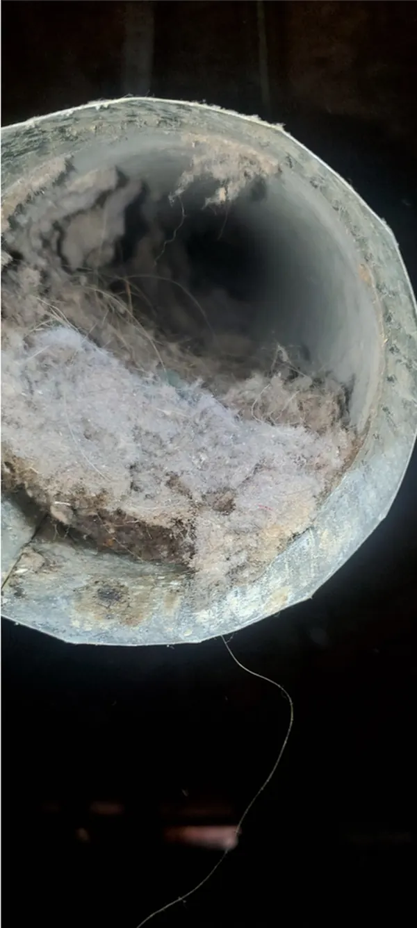 Dryer vent line before cleaning, caked with lint