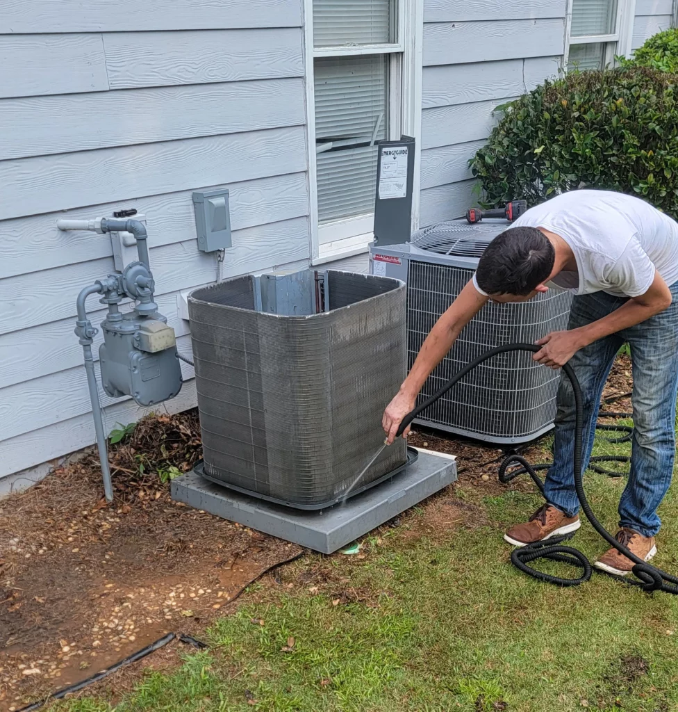 Man cleaning around outside AC unit