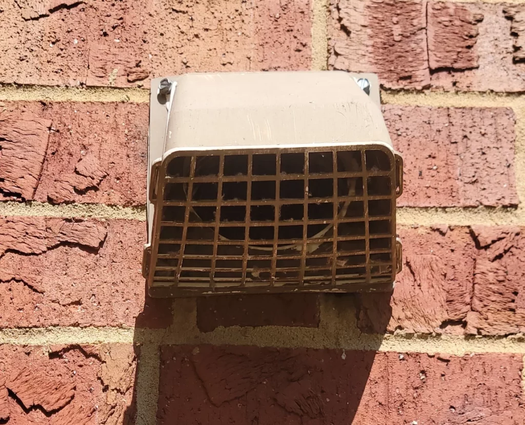 Clean outside dryer vent on brick wall